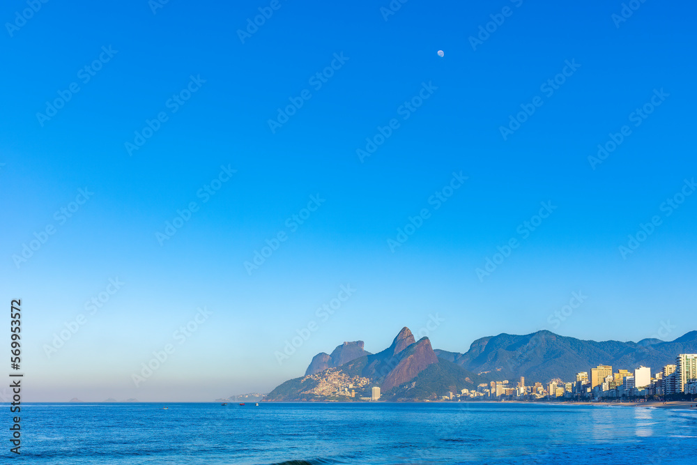 Sunrise on Ipanema beach in Rio de Janeiro with the moon in the sky