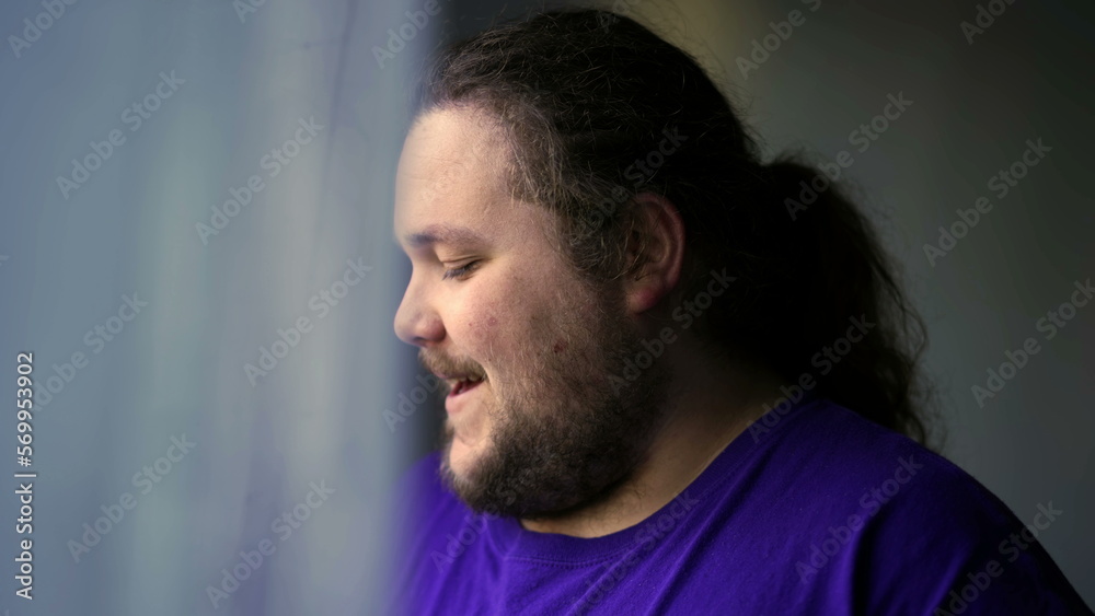 One happy casual chubby man smiling by home window looking out One happy casual chubby man smiling by home window looking out