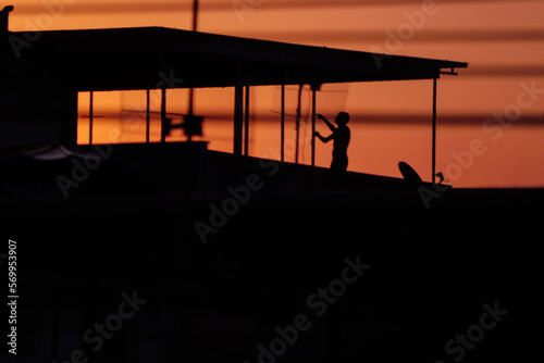 Garoto soltando pipa no entardecer na laje