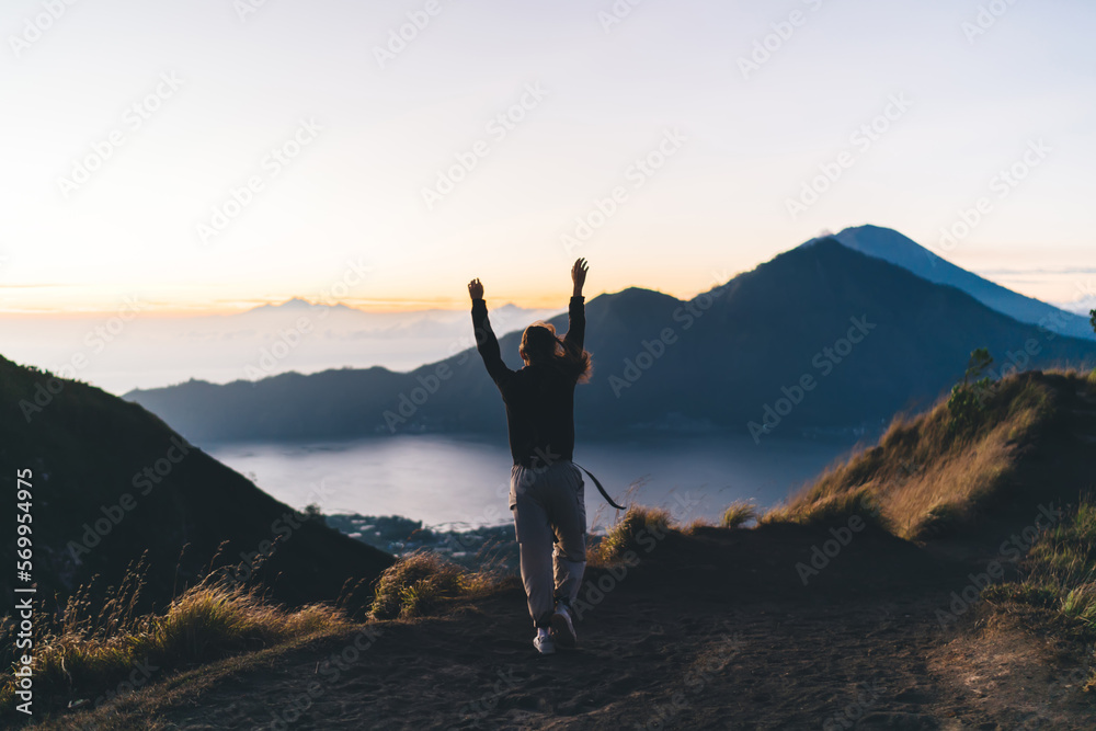 Faceless woman walking on mountain and spreading arms
