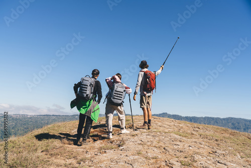 Group of tourists with trekking poles standing on hill in highlands