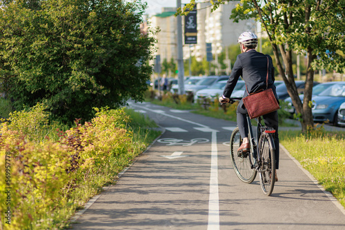 Foto Stylish businessman in helmet cycling on bike path in sunny day.