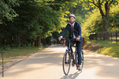 Fotografia Smiling office clerk feeling great, while cycling from work in park