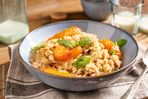 Millet groats dessert with caramelised apricots, almonds and mint leaves. Breakfast bowl.