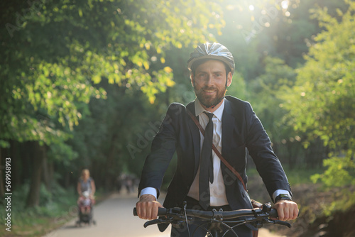 Happy attractive businessman riding bicycle on way to work. photo