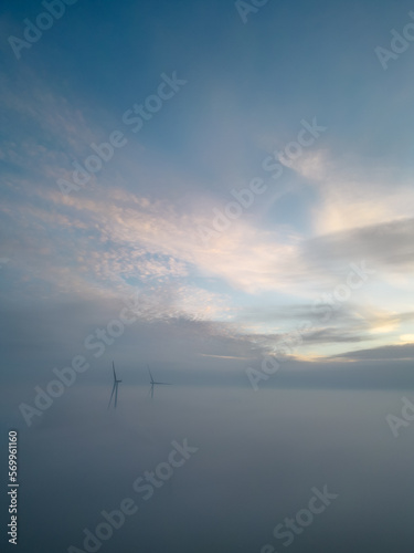 Aerial view of wind turbines or windmills farm field in industry factory with fog. Power, sustainable green clean energy, and environment concept. Nature preservation innovation. High quality photo