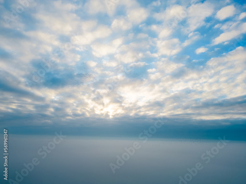 Aerial View. Flying in fog, fly in mist over the early morning clouds in the rising sun. Aerial camera shot. Flight above the clouds towards the sun with the mist clouds floating by. Misty weather © Bjorn B