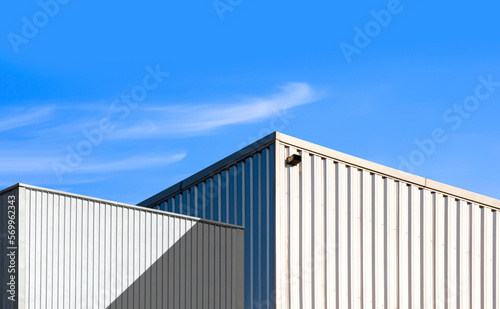 Low angle view of corrugated steel Warehouse next to Industrial Building against blue sky Background
