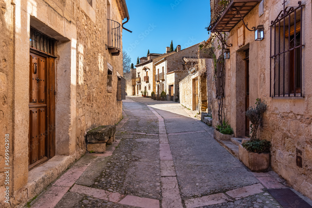 Narrow alley with stone houses and wooden gates in the picturesque medieval village of Pedraza, Segovia, Spain.