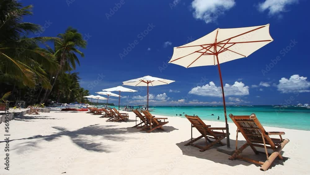 Sun umbrellas and beach chairs on tropical beach with palm trees. Summer vacation. Boracay