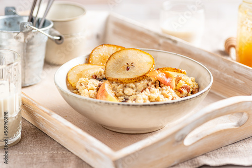 Millet groats dessert with caramelised pears, apples almonds and mint leaves. Breakfast bowl.