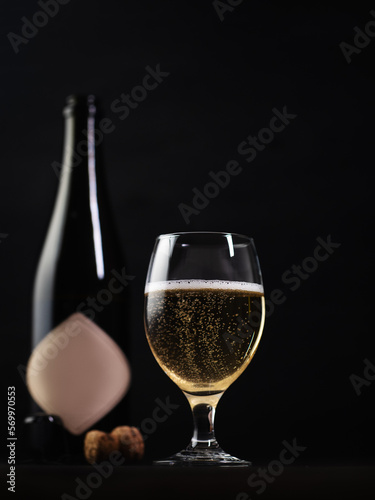 Glass and bottle of cider, black background.