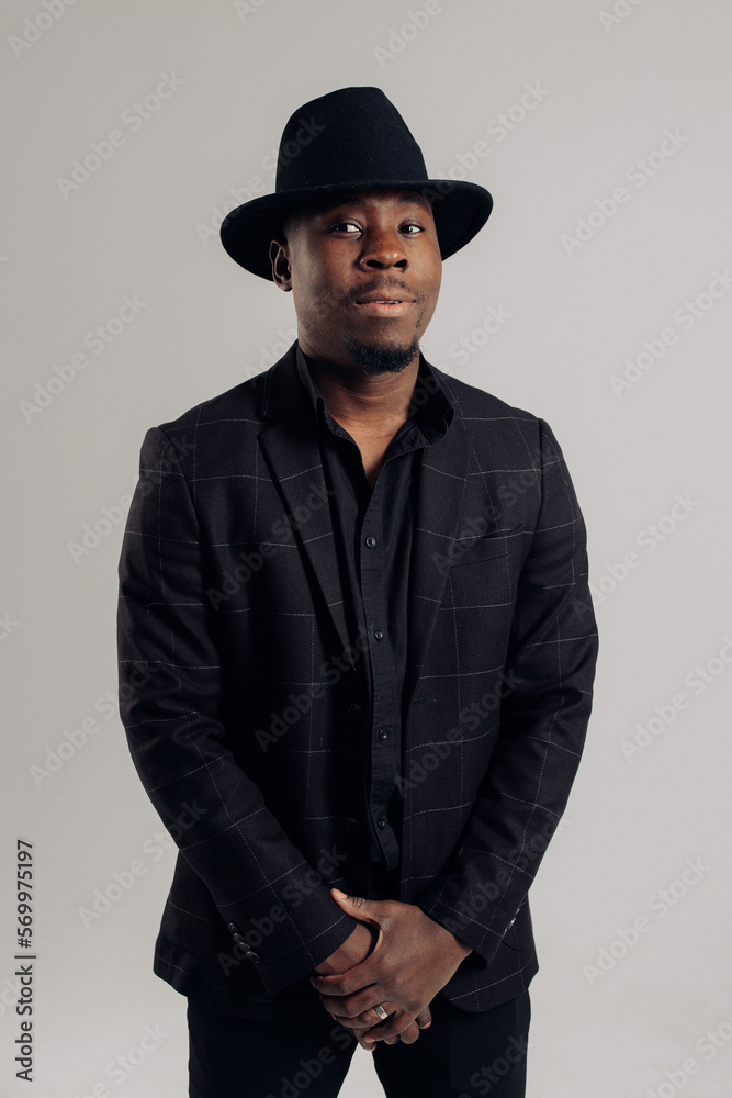 Young african man in suit and hat stands against gray background. Young african man in suit and hat stands against gray background.