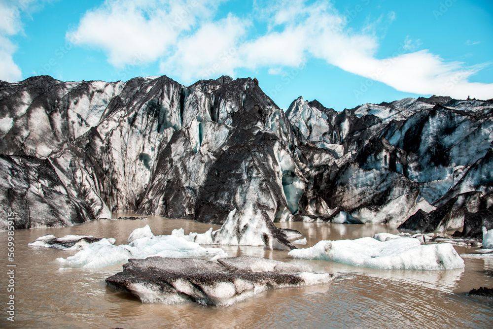 Charming beautiful scenery with nice ice blocks and glacier in volcanic soot in Solheimajokull lagune, Iceland. Exotic countries. Amazing places. Popular tourist atraction. (global warming – concept)
