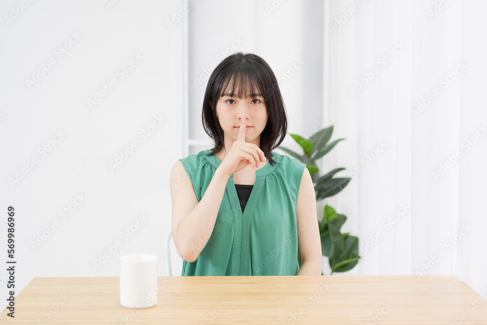 リビングで内緒のポーズをする若い女性 リビングで内緒のポーズをする若い女性