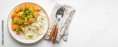 Traditional Indian dish chicken curry with basmati rice and fresh cilantro on rustic white plate on white concrete table background from above. Indian dinner meal, space for text