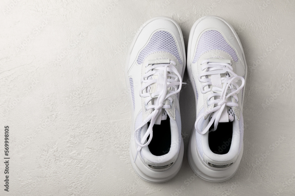 Pair of white shoes on a white texture background. Sport shoes. Unisex. Street style. Pair of white shoes on a white texture background. Sport shoes. Unisex. Street style.