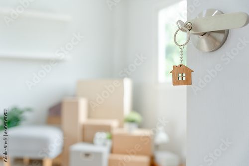 Moving house, relocation. The key was inserted into the door of the new house, inside the room was a cardboard box containing personal belongings and furniture. move in the apartment or condominium. © Shisu_ka