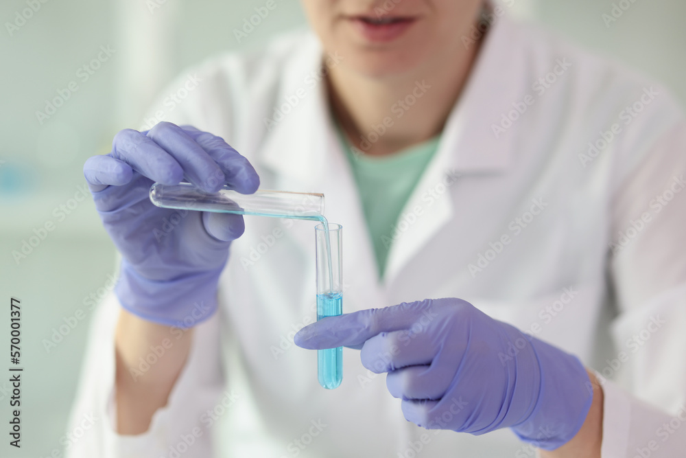 Gloved female scientist holds two test tubes of liquid in her hands close-up. Gloved female scientist holds two test tubes of liquid in her hands close-up.