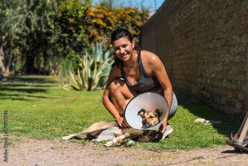 young and beautiful woman caring for her injured dog, on the grass on a sunny day