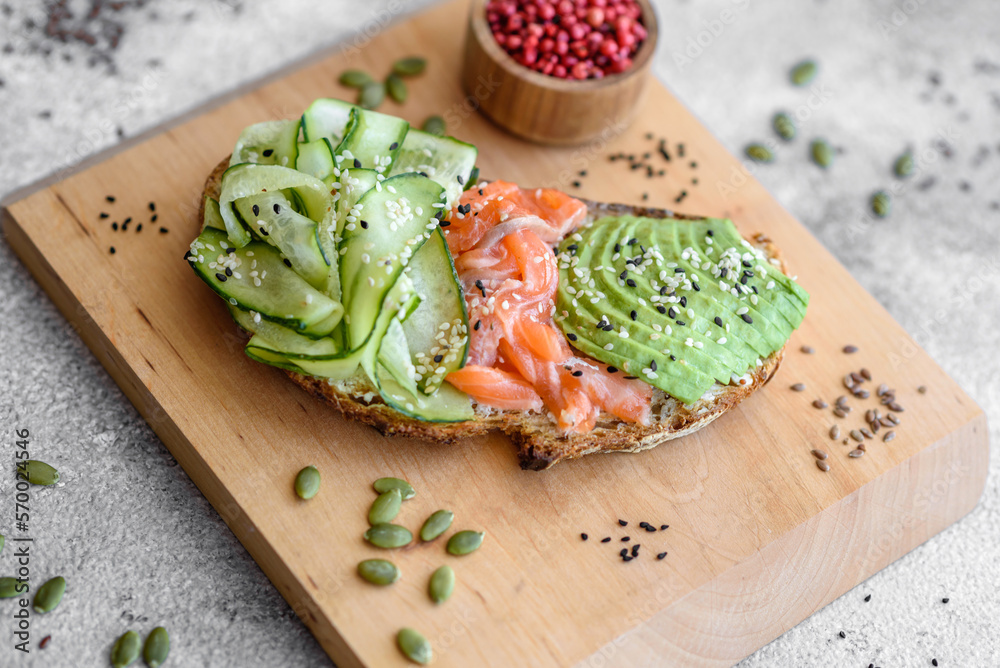 Delicious brown bread toast with salmon, avocado, cucumber and sesame seeds Delicious brown bread toast with salmon, avocado, cucumber and sesame seeds