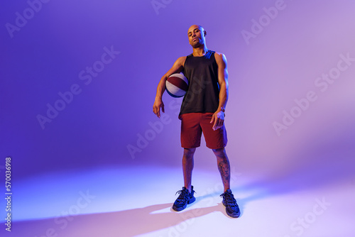 Full length portrait of a basketball player with ball on studio background. Advertising concept