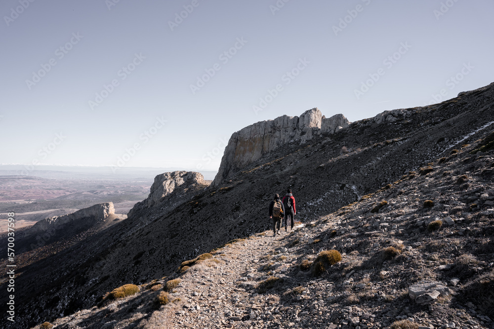 Two young male friends are hiking next to a mountain with big limestone formations
