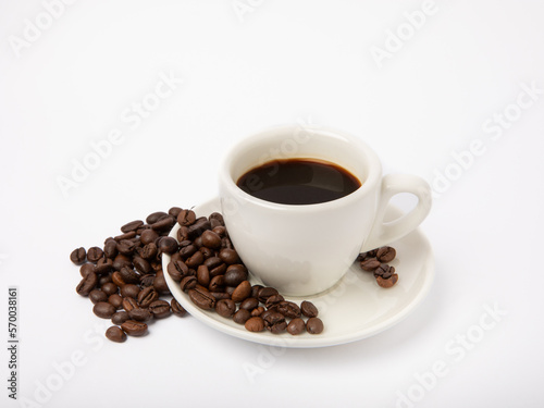 Coffee beans and a cup of stale strong espresso isolated on white background.