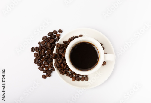 Coffee beans and a cup of stale strong espresso isolated on white background.