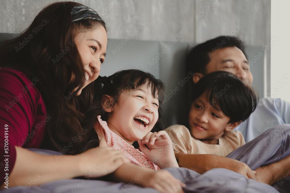 Handsome young Asian father embracing and hugging cute little Asian boy and son while preparing for for a good night sleep at home on a comfortable bed Handsome young Asian father embracing and hugging cute little Asian boy and son while preparing for for a good night sleep at home on a comfortable bed