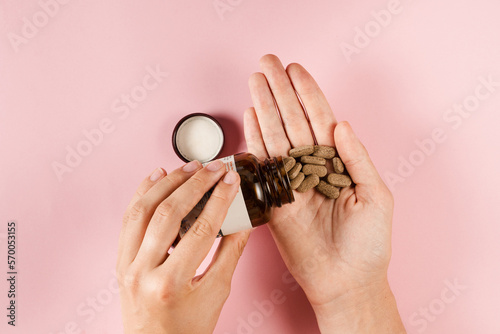 Fototapete Tablets of dietary supplements in hand for daily pills intake on pink background