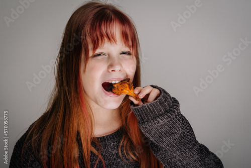 A young girl eats a chicken