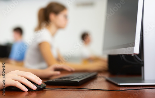Closeup schoolgirl using computer mouse with computer keyboard in computer class