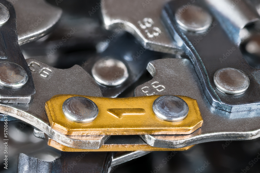 Closeup of replaceable cutting chain from metal links joined by rivets for portable chainsaw guide bar. Sharp steel part detail of power tool on blur background. Equipment to professional wood sawing.