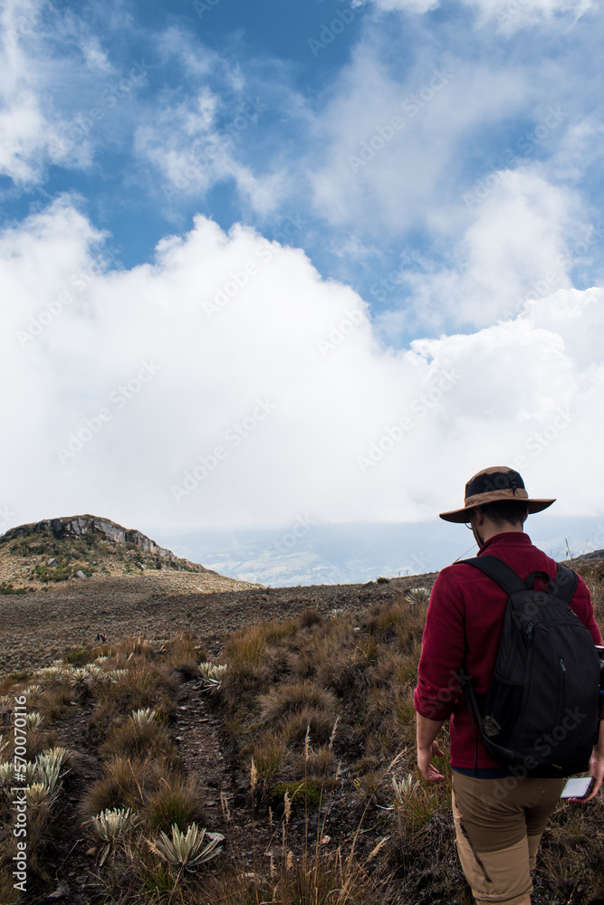 Man walking through paramo mountain path in a cloudy day