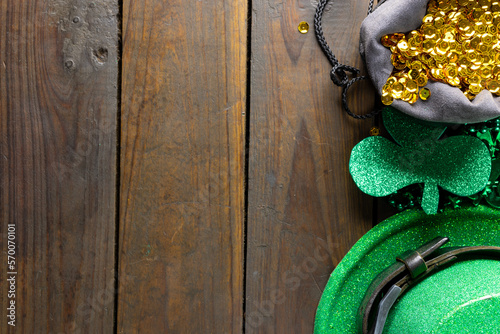 Image of green hat, green clover, gold sequins and copy space on wooden background