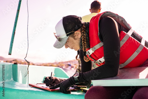 Marine biologist writing data on top of a boat photo