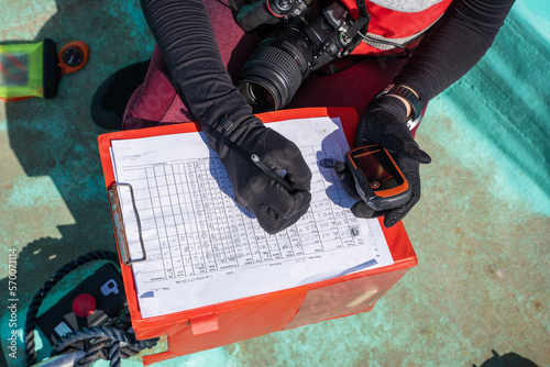 Unrecognizable marine biologist writing data on paper on a boat photo