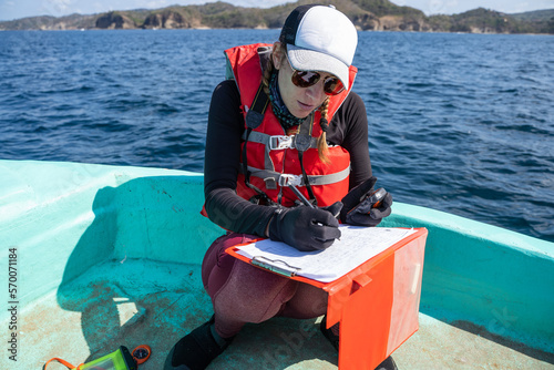 Equipped marine biologist writing notes on a boat