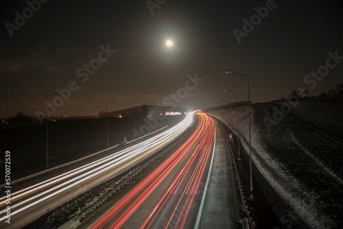 smugi świateł jadących nocą aut autostradą w świetle księżyca