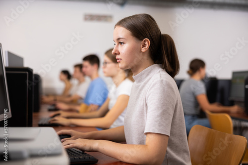 Side view on diligent college girl studying using pc in computer class in library