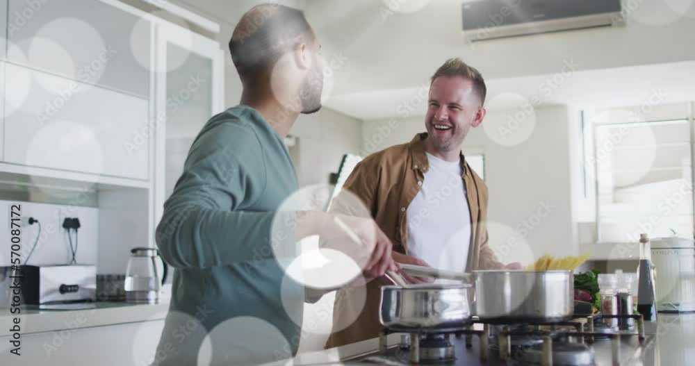 Animation of light spots over diverse male couple cooking dinner in kitchen Animation of light spots over diverse male couple cooking dinner in kitchen