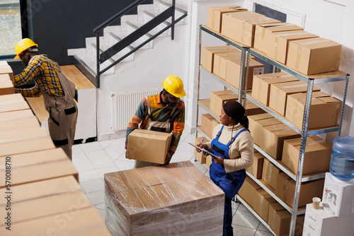 Billede på lærred Package handler holding parcel and talking with supervisor in warehouse