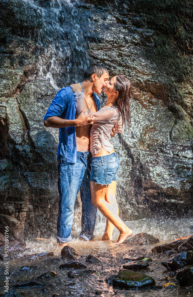 Happy young couple in love outdoors in the waterfall