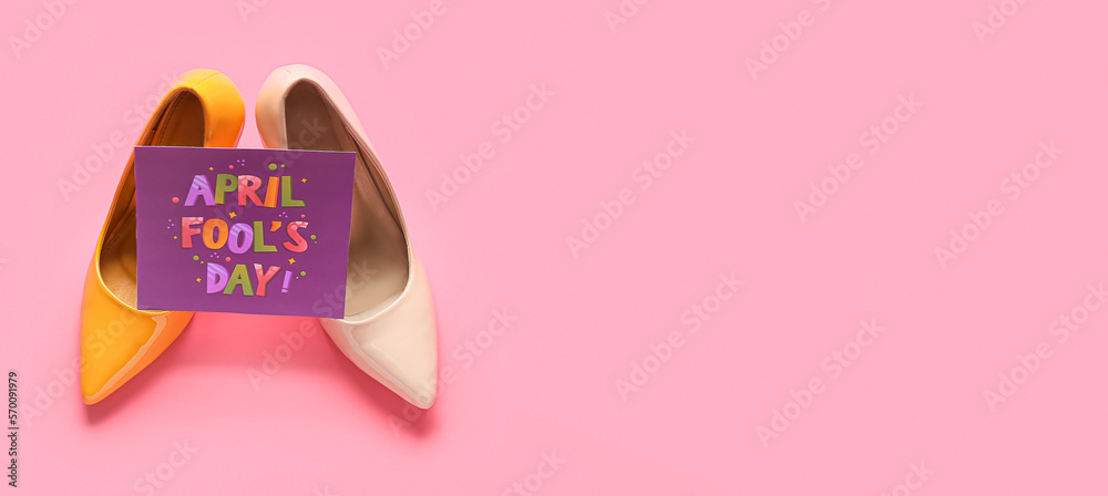 Fototapeta premium Shoes and card with text APRIL FOOL'S DAY on pink background with space for text