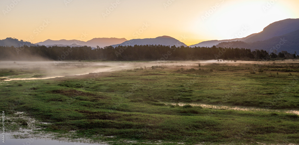 Beautiful sunrise over mountains and marshland in summer