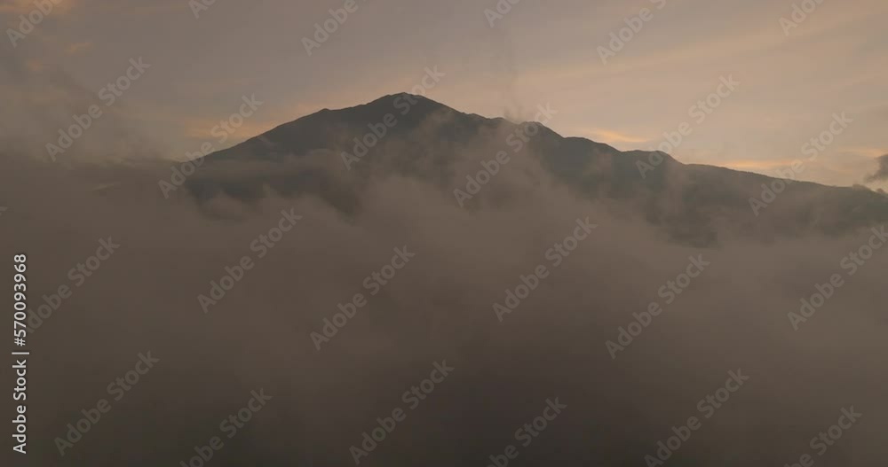 Aerial Slow Motion Shot Of Famous Volcanic Mountains At Sunset, Drone Flying Forward Over Clouds In Sky - Java, Indonesia Aerial Slow Motion Shot Of Famous Volcanic Mountains At Sunset, Drone Flying Forward Over Clouds In Sky - Java, Indonesia