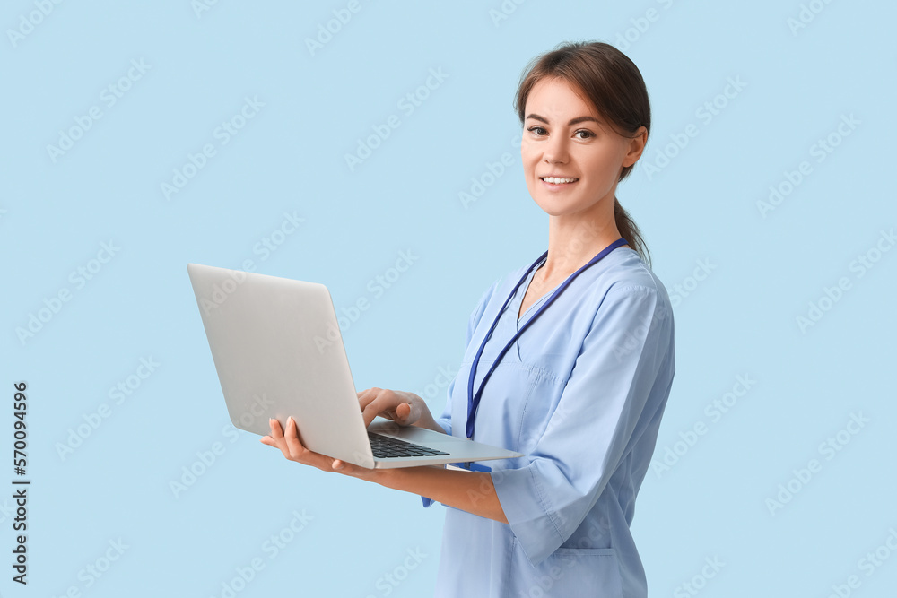 Female medical intern using laptop on blue background Female medical intern using laptop on blue background
