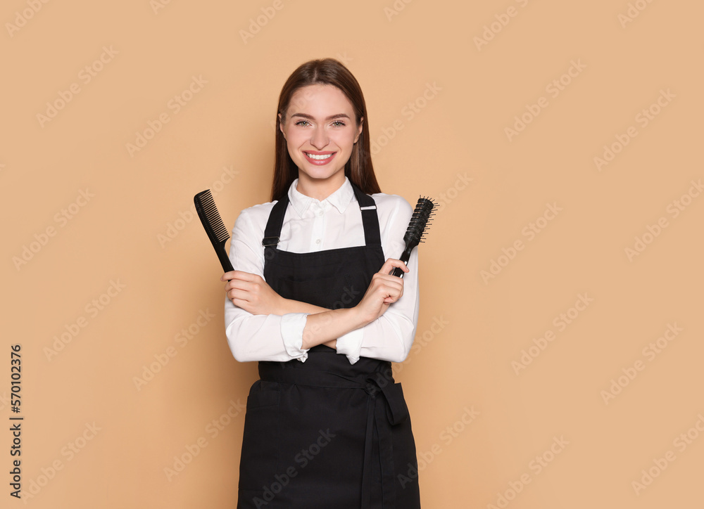 Portrait of happy hairdresser with brush and comb on beige background. Space for text Portrait of happy hairdresser with brush and comb on beige background. Space for text
