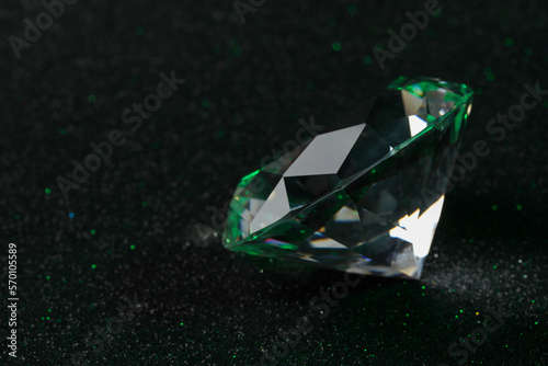 Beautiful dazzling diamond on dark glitter surface, closeup. Space for text